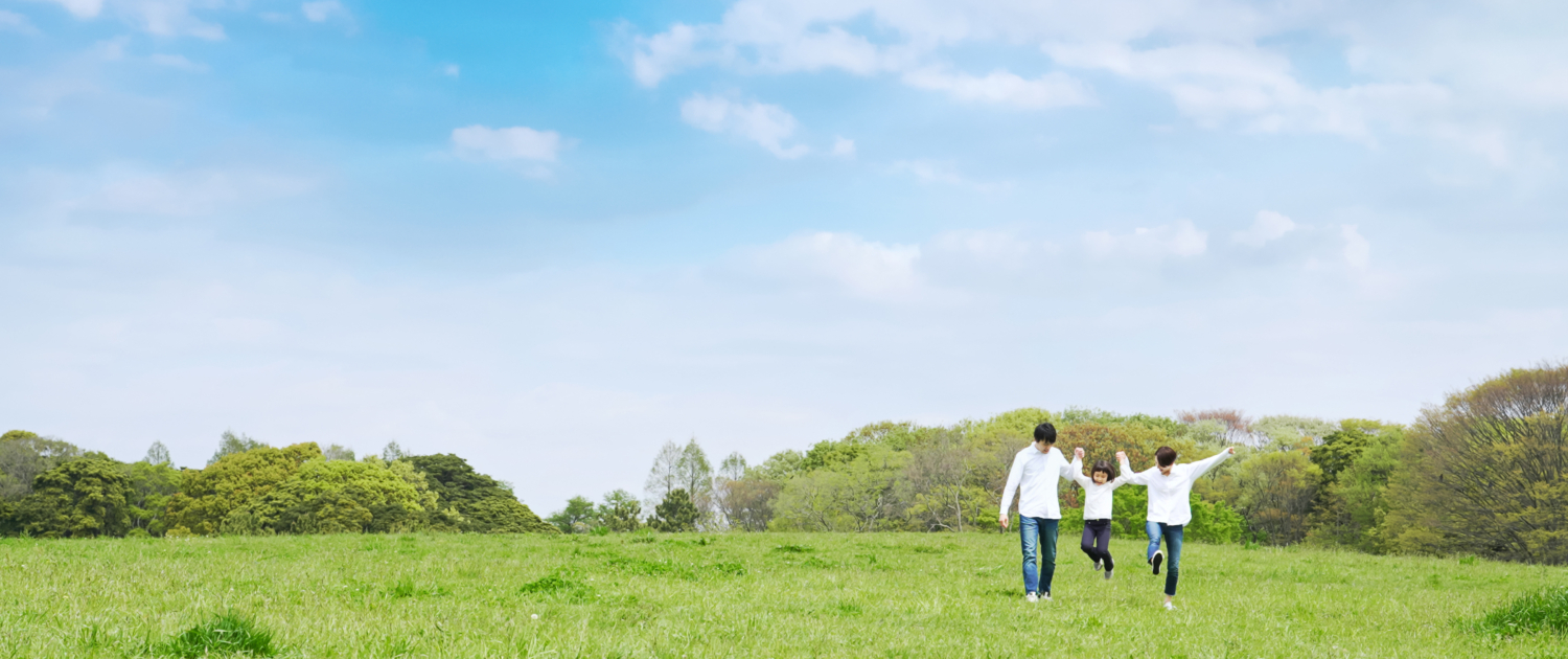 青空の草原を歩く家族 環境 子育て